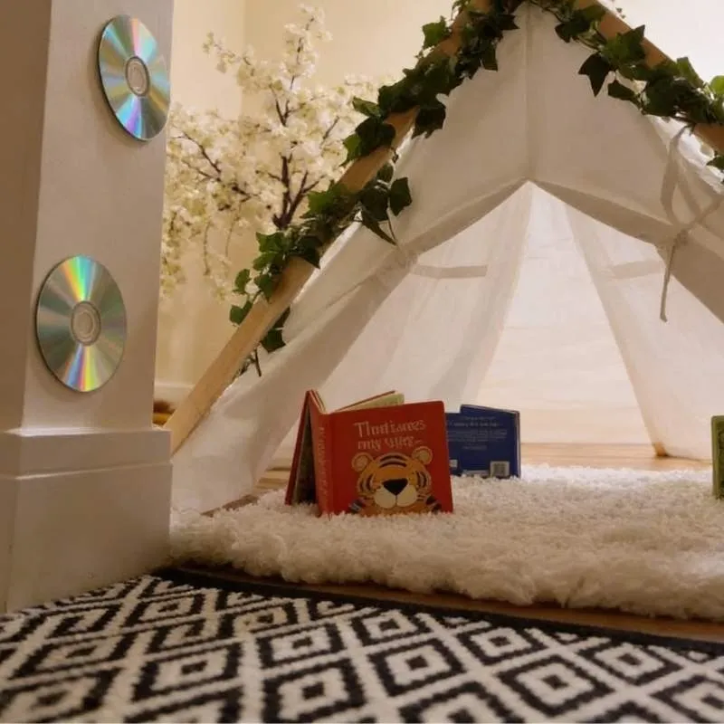 A colorful teepee tent filled with books and toys, promoting creativity and play for children.
